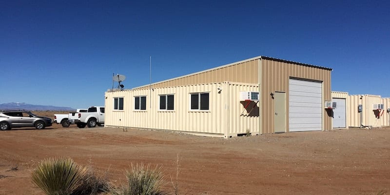 A building in the desert with vehicles outside