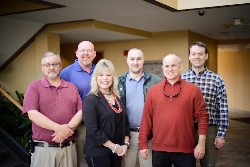 A group of 6 people standing in an open room